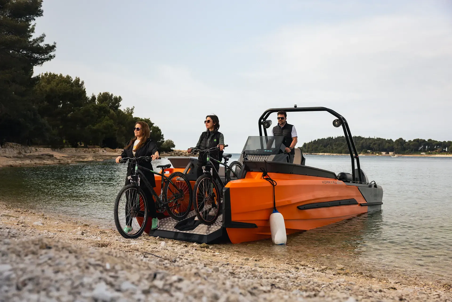 Korkyra 650 Pro varada en la orilla con tres personas y sus bicicletas junto a la plataforma de carga delantera
